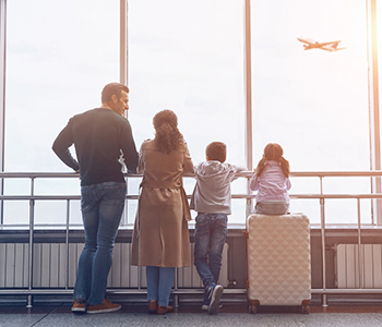 Family watching airplane from airport terminal window