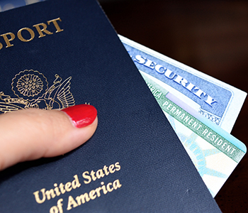 Hand holding US passport with green card and Social Security card